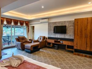 a living room with two chairs and a television at Laalis crest Coorg Madikeri in Madikeri