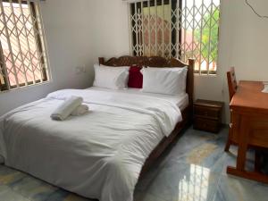 a bedroom with a large bed with white sheets and a desk at Tranquility Lodge in Abrekuma