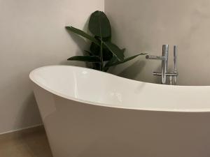 a white bath tub with a plant in a bathroom at Calheta Suites - Vinha & Jardim - Adults-only suites met hottub & zeezicht in Calheta +13 photos