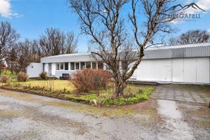 a white building with a tree in front of it at Kleppjárnsbraut in Kleppjárnsreykir