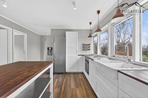 a kitchen with white cabinets and a sink and windows at Kleppjárnsbraut in Kleppjárnsreykir