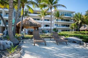 two chairs and a umbrella and a building at Costa Brava Apartments I Ocean Front in Puerto Aventuras
