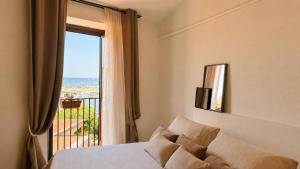 a bedroom with a bed and a view of the ocean at Almarìa - Le case del Castello - San Nicola L'Arena - Trabia in Trabia
