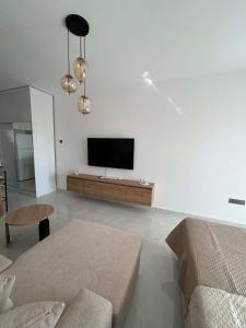 a living room with a couch and a tv on a wall at New Luxury Studio In Caesar Resort & Spa in Dherinia