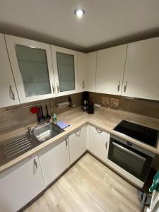 a small kitchen with white cabinets and a sink at Ferienwohnung "Auszeit" in Dobra