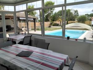 a dining room with a table and a view of a pool at Chambres d'hôtes Les Écureuils in Saint-Laurent-de-la-Prée
