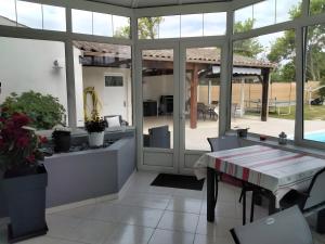 a screened in porch with a table and a patio at Chambres d'hôtes Les Écureuils in Saint-Laurent-de-la-Prée