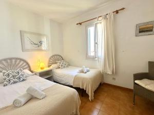 a bedroom with two beds and a window at White Sands 4.20 in Arenal d'en Castell +22 photos
