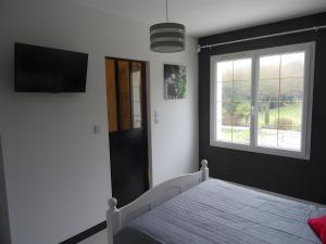 a bedroom with a bed with a television and a window at Chambres d'hôtes Les Écureuils in Saint-Laurent-de-la-Prée
