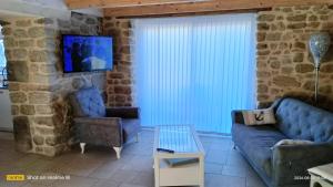 a living room with a couch and a tv on a stone wall at Ty Penty in Riantec