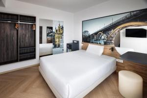 a bedroom with a white bed and a picture of a bridge at B&B Hotel Maribor in Maribor