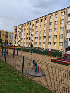a playground in front of a large building at Apartament Targowa 9A41 in Uniejow