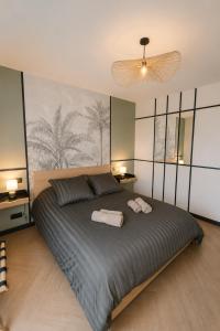a bedroom with a large bed with two towels on it at M a g i c & J u n g l e in Verdun-sur-Meuse