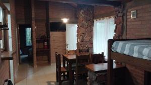 a room with a bed and a table and chairs at Cabañas Rio de Oro in Mina Clavero