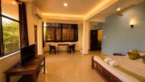 a bedroom with a bed and a desk and a table at Colors Fly Hotel in Colva