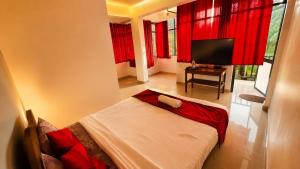 a bedroom with a bed with red curtains and a television at Colors Fly Hotel in Colva