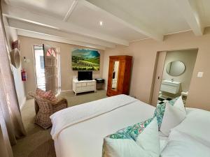 a bedroom with a large white bed and a television at Mont d'Or Franschhoek in Franschhoek