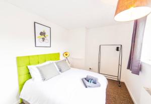 a bedroom with a white bed with a green headboard at 4 Bed - 2 Baths 1 Walk in Shower Lots of Parking in Ipswich