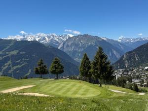a golf course on a hill with mountains in the background at Verbier city centre, chalet Valmont in Verbier