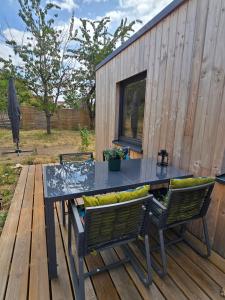 a table and chairs on a deck with a building at La tiny de Miss Purple in Chantelle