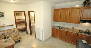a kitchen with wooden cabinets and a living room at Villaggio Turistico Sole e Mare in Nisporto