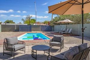 a pool with chairs and a table and an umbrella at Tucson Oasis by Rather Be Properties in Tucson