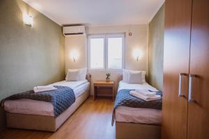 two beds in a small room with a window at Artelo - Inspired Stay in Bitola