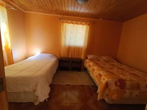 two beds in a small room with a window at Cabañas Wiñaypacha Putre in Putre