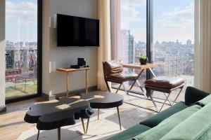 a living room with a couch and chairs and a tv at Arlo Williamsburg in Brooklyn