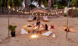 two women sitting on pillows on the beach at night at MADIROKELY HOUSE Nosy Be in Ambatoloaka