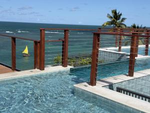 a swimming pool with a sail boat in the ocean at Smeralda del Mare by AFT in Porto De Galinhas