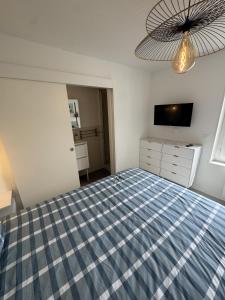 a bedroom with a blue and white bed and a television at Sam's cocoon in Vicq-sur-Nahon