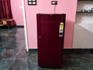 a red refrigerator in front of a pink wall at Omkar Homestay - Honavar in Kāsarkod