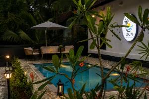 a resort pool with a table and chairs and an umbrella at Udupi River Inn in Kalyānpur