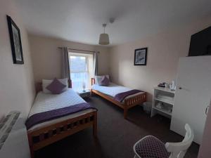a bedroom with two beds and a window at O'Loughlin's Bar in Milltown Malbay