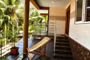 a chair on the balcony of a house with palm trees at Omkar Homestay - Honavar in Kāsarkod