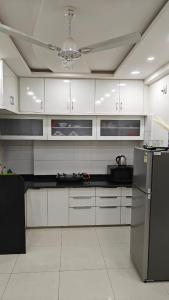 a kitchen with white cabinets and a black refrigerator at 2bhk penthouse with open tarace in Vadodara
