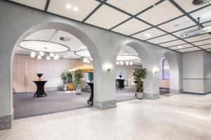 a lobby with arches and plants in a building at Holiday Inn Werribee by IHG in Werribee
