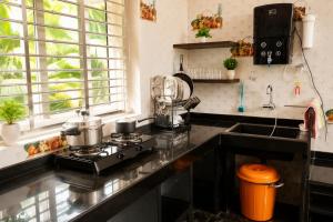 a kitchen with a stove top oven next to a sink at Omkar Homestay - Honavar in Kāsarkod