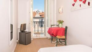 a room with a table and a television and a balcony at Hotel Solara in Nice