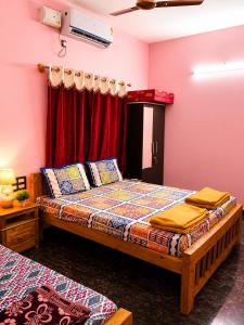 a bedroom with two beds and a red curtain at Omkar Homestay - Honavar in Kāsarkod