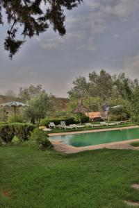 a swimming pool with chairs and umbrellas in a yard at Dar TOUFTEN in Agouni