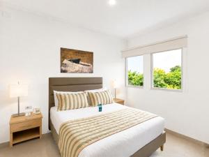 a white bedroom with a bed and a window at Hotel Neiva Plaza in Neiva