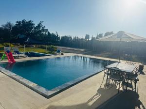 a swimming pool with a table and an umbrella at Sisi villa in Essaouira