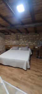 a bedroom with a white bed in a stone wall at Habitació doble Àger in Àger