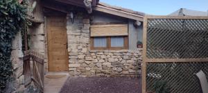 a stone building with a wooden door and a fence at Habitació doble Àger in Àger +8 photos