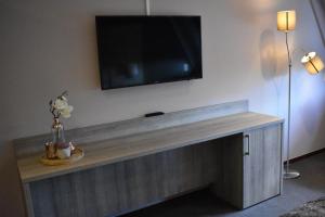 a flat screen tv on a wall with a wooden table at Hotel De Vrouwe van Stavoren in Stavoren
