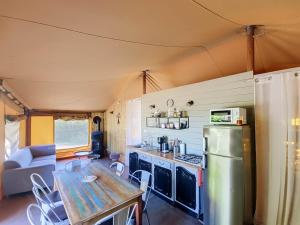 a kitchen and living room with a table and a refrigerator at Lodge La Vie Douce in Vigeois