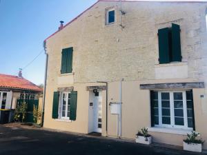 an old brick building with green shutters on a street at la colombe du marais in Courçon