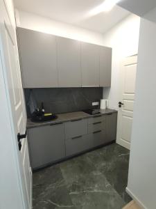a kitchen with white cabinets and a tile floor at UrbanHome1 in Rokiškis